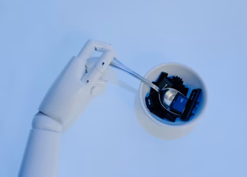 A robotic hand holds a spoon filled with keyboard keys, symbolizing AI and technology fusion.