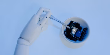 A robotic hand holds a spoon filled with keyboard keys, symbolizing AI and technology fusion.