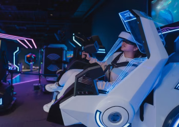 A woman enjoying a virtual reality ride in a futuristic, neon-lit arcade setting.
