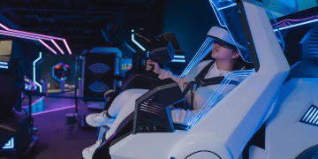 A woman enjoying a virtual reality ride in a futuristic, neon-lit arcade setting.