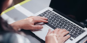 Focused view of a person typing on a laptop, showcasing productivity and technology.