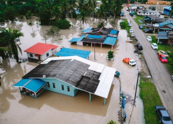 Aerial view of a flooded village in Kijal, Terengganu, Malaysia, showcasing submerged houses and streets.