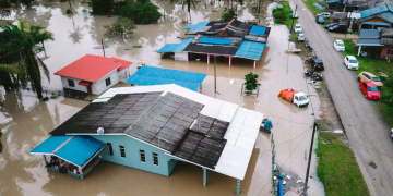 Aerial view of a flooded village in Kijal, Terengganu, Malaysia, showcasing submerged houses and streets.