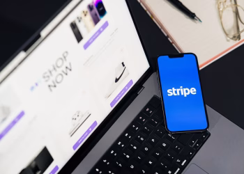 Mobile phone displaying Stripe app on a laptop with an eCommerce site open, symbolizing online shopping.