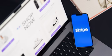Mobile phone displaying Stripe app on a laptop with an eCommerce site open, symbolizing online shopping.