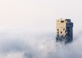 A skyscraper towers above Dubai's foggy skyline, capturing the serene majesty of urban architecture.
