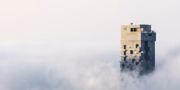 A skyscraper towers above Dubai's foggy skyline, capturing the serene majesty of urban architecture.