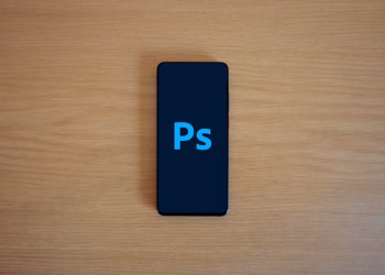 Top view of a smartphone showing Adobe Photoshop on a wooden surface.