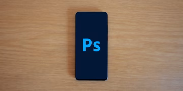 Top view of a smartphone showing Adobe Photoshop on a wooden surface.
