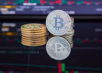 Bitcoin coins stacked in front of cryptocurrency trading chart reflecting market trends.