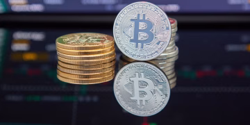 Bitcoin coins stacked in front of cryptocurrency trading chart reflecting market trends.