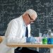 Scientist in lab coat working at desk with formulas.