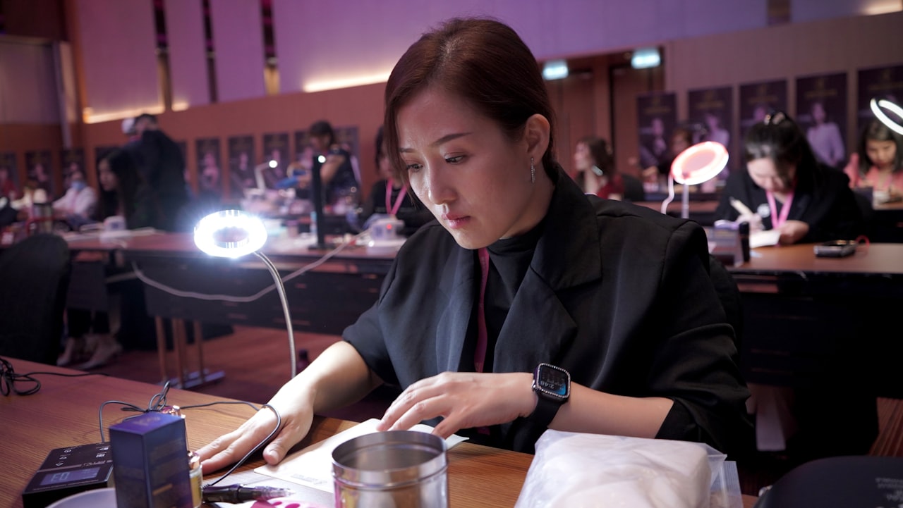 a woman sitting at a table working on a cell phone