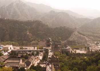 A scenic aerial view of the Great Wall of China surrounded by lush mountains in spring.