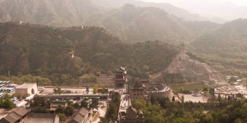 A scenic aerial view of the Great Wall of China surrounded by lush mountains in spring.