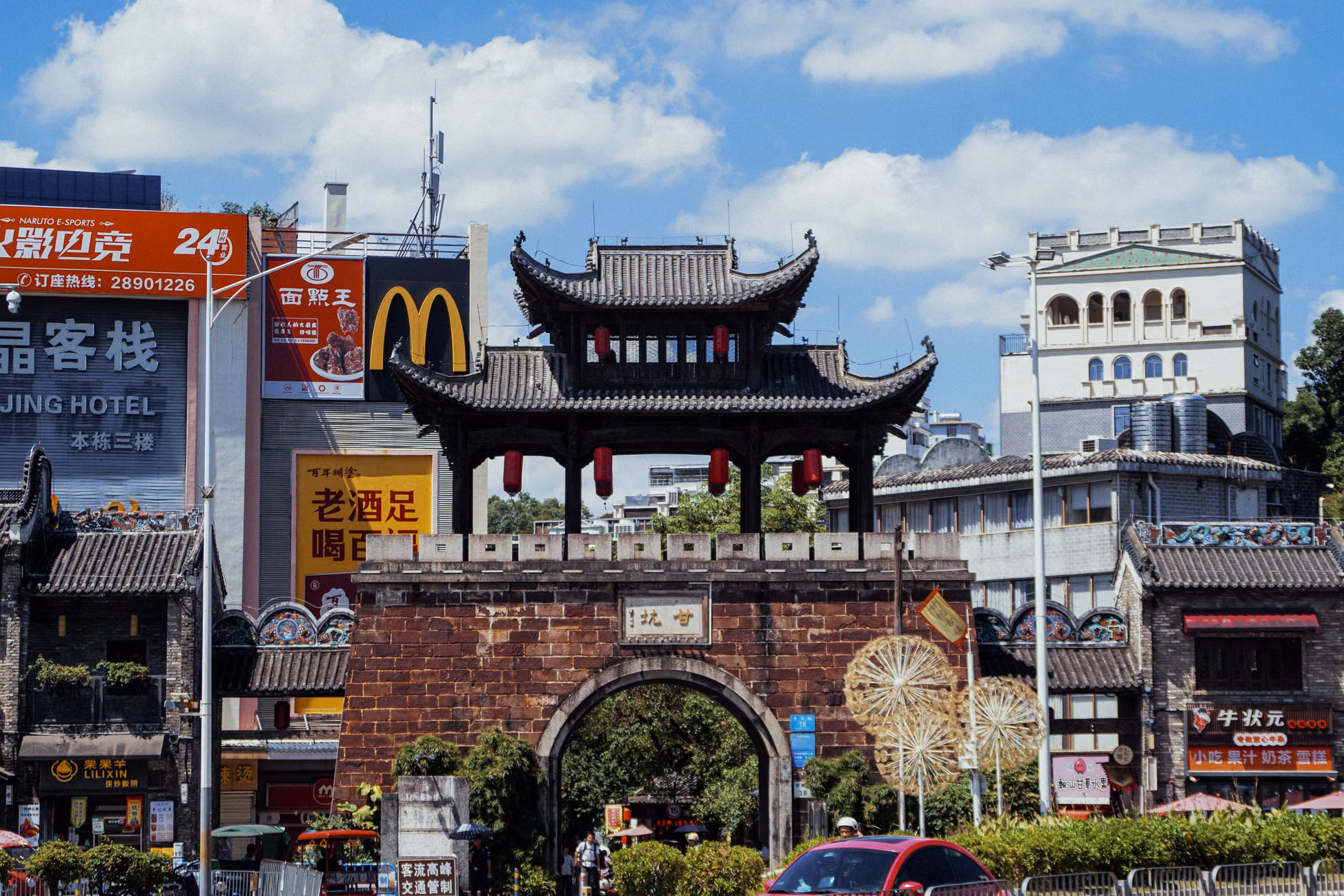 Traditional Chinese gate amidst modern buildings on a sunny day.