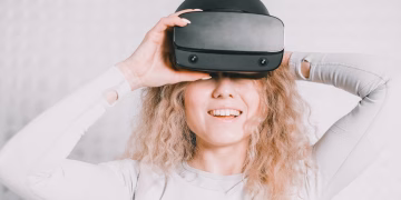 Smiling woman wearing a VR headset and experiencing virtual reality excitement.