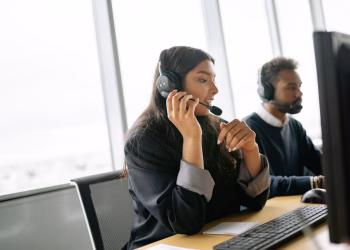 Customer service agents using headsets and computers in a modern office environment.