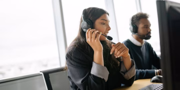 Customer service agents using headsets and computers in a modern office environment.