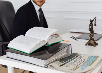 A lawyer sitting at a desk with legal books, documents, and a newspaper, embodying professionalism.