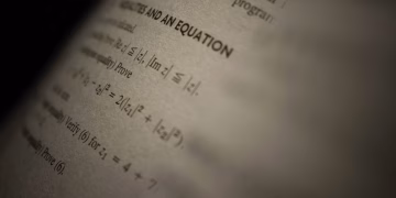 Selective focus on a mathematics textbook page with complex equations and text.