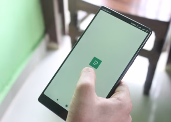 Detailed view of a hand holding a smartphone indoors, showcasing modern technology usage.