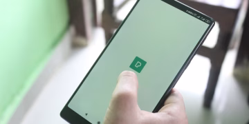 Detailed view of a hand holding a smartphone indoors, showcasing modern technology usage.