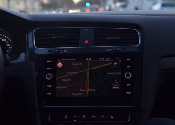 Interior of modern car with steering wheel and navigation system showing route through city streets