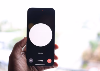 Close-up of a hand holding a smartphone displaying a voice assistant interface.
