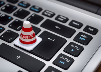 Miniature caution cone on a computer keyboard symbolizing data security and control.