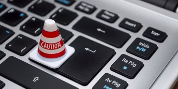 Miniature caution cone on a computer keyboard symbolizing data security and control.
