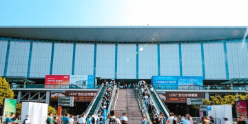 People entering Shanghai exhibition center via outdoor escalator during daytime.
