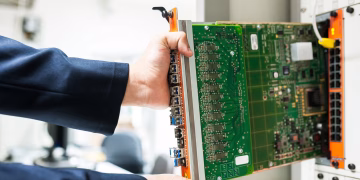A technician inserts a circuit board into a server rack, illustrating technology and connectivity.