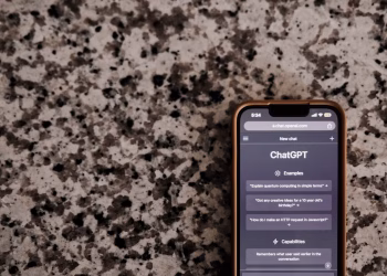 Close-up of a smartphone with ChatGPT interface on a speckled surface, highlighting technology and AI.