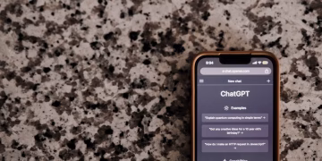 Close-up of a smartphone with ChatGPT interface on a speckled surface, highlighting technology and AI.