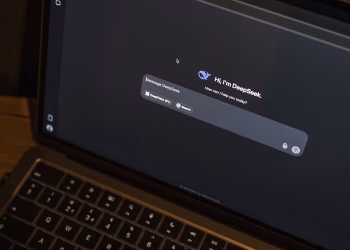 A laptop on a wooden table shows an AI chat interface, featuring the DeepSeek chatbot in action.