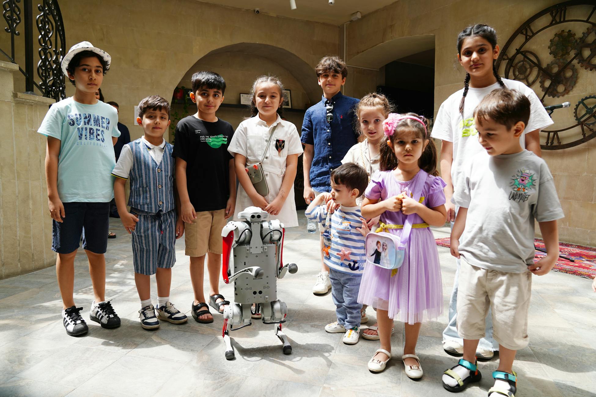 A diverse group of children joyfully interacting with a humanoid robot indoors, showcasing future technology.