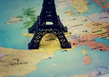 Miniature Eiffel Tower placed on a map of Europe, focusing on France.