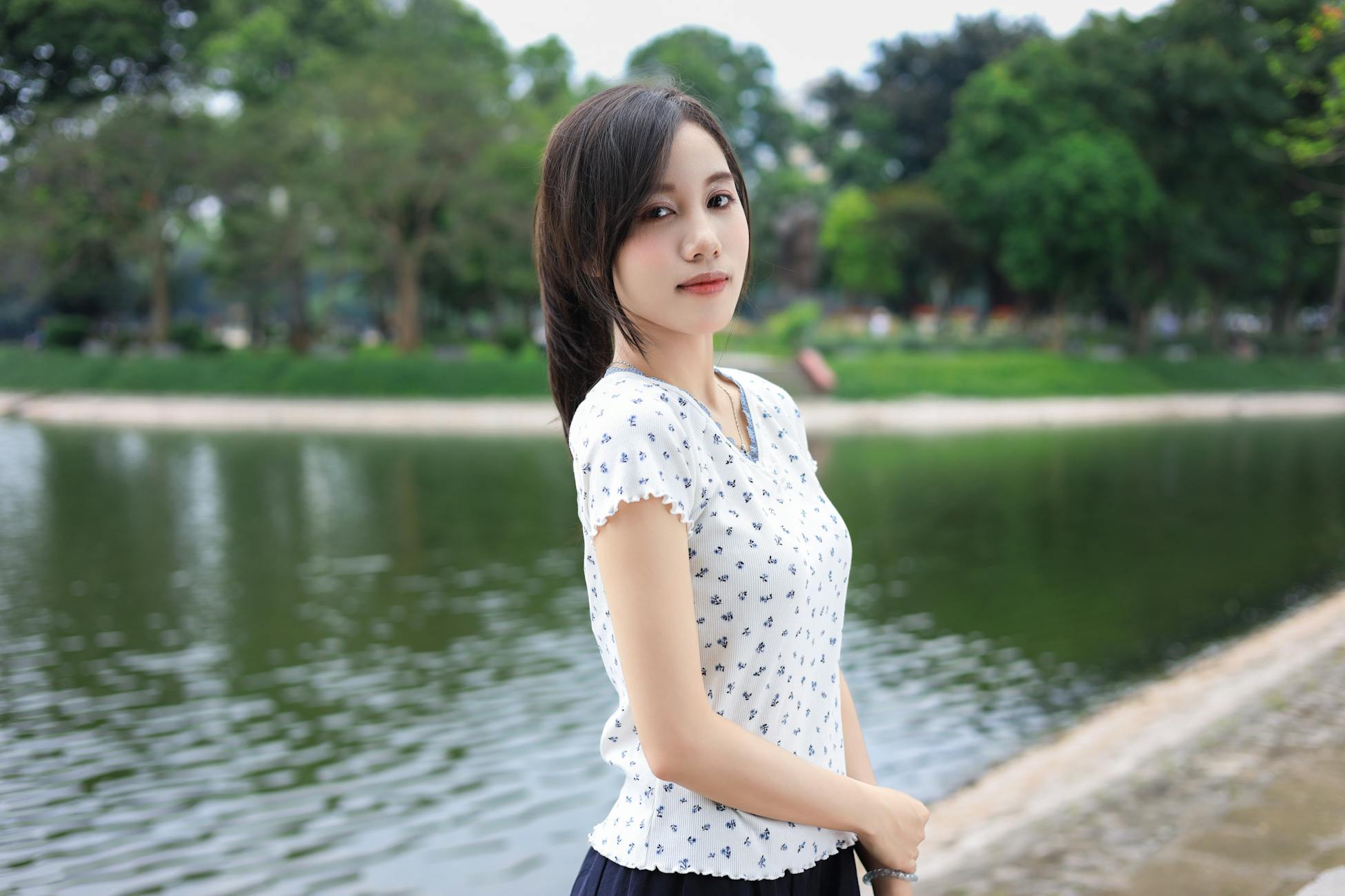 A contemplative woman stands by a serene lakeside setting in Vietnam, embracing nature.
