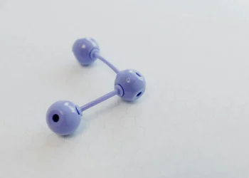 Abstract representation of a molecular structure using a purple plastic model on hexagonal patterned paper.