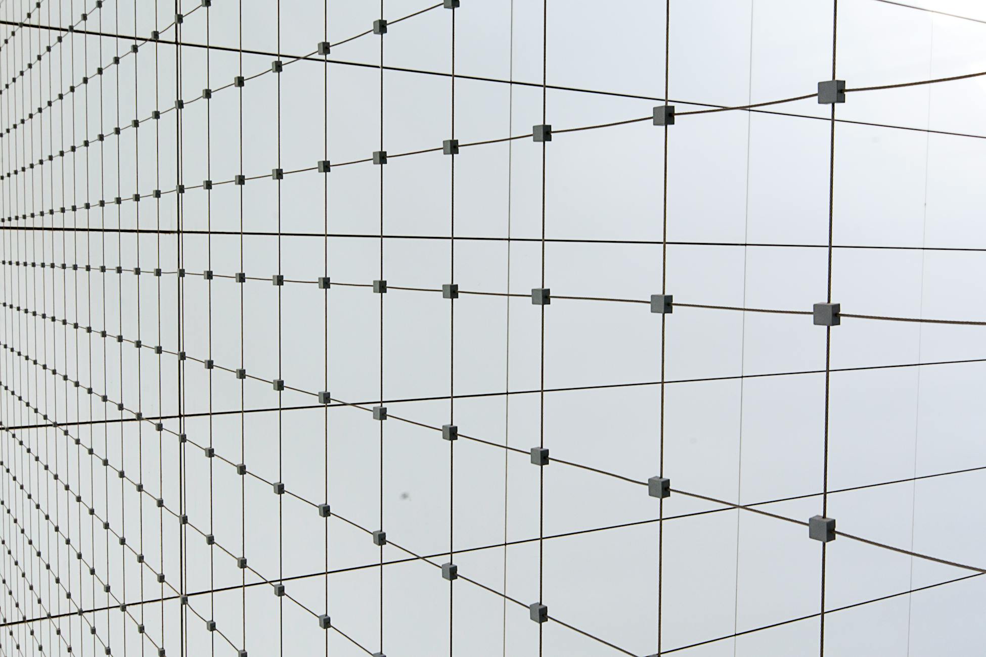 Abstract view of a glass wall with intersecting grid lines creating a modern geometric pattern.