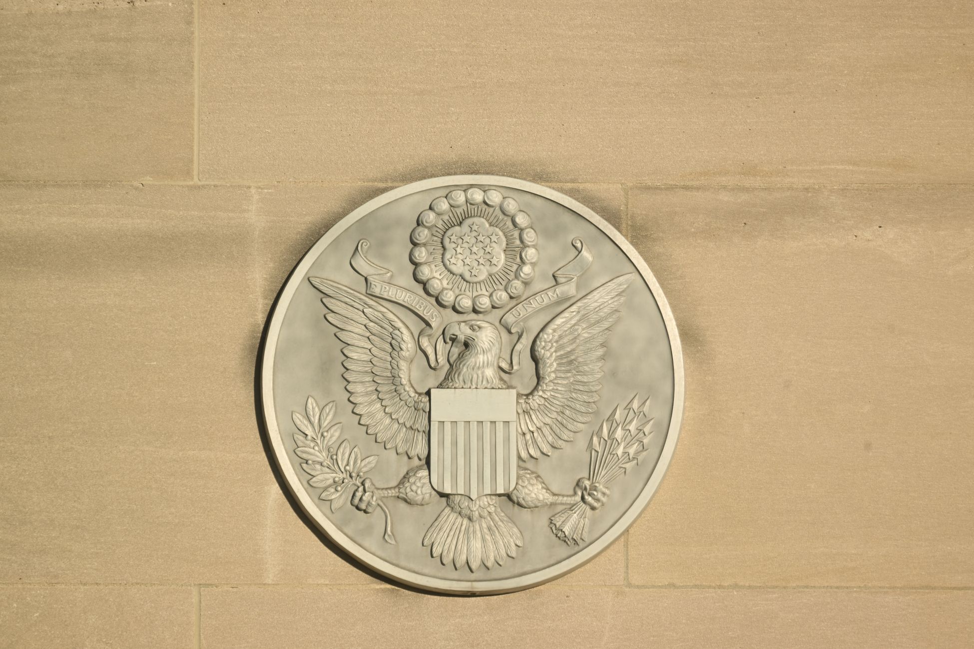 Stone carving of the Great Seal of the United States on a wall displaying an eagle with shield and olive branch.