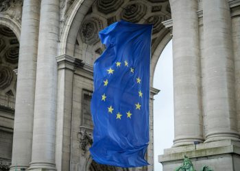 European Union flag fluttering beneath the Cinquantenaire Arch in Brussels, Belgium.