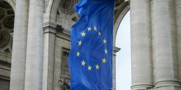 European Union flag fluttering beneath the Cinquantenaire Arch in Brussels, Belgium.