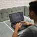 A man working on a laptop in a cozy, modern office space with a focus on technology.