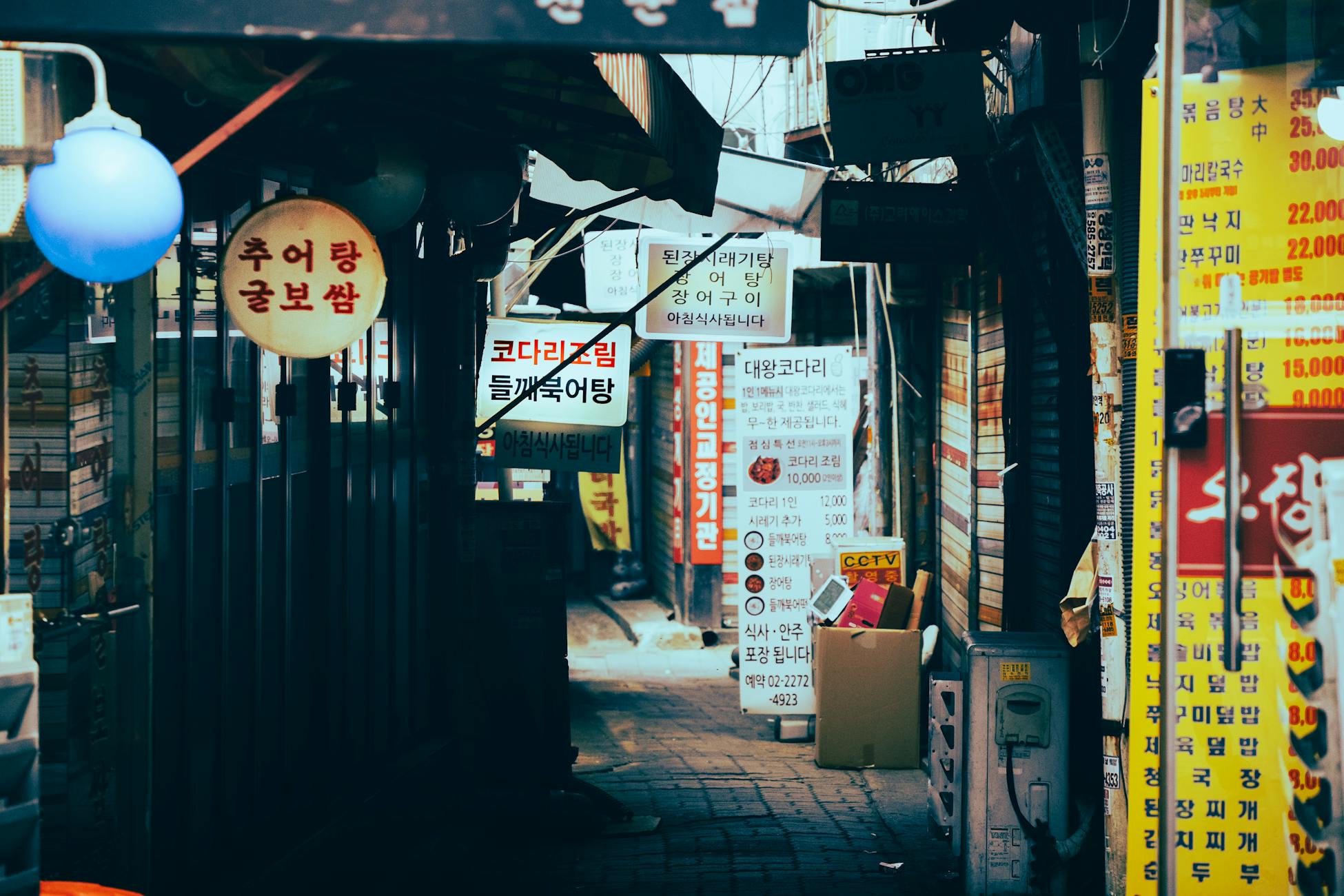 Vibrant narrow alley filled with colorful signs and bustling market atmosphere.