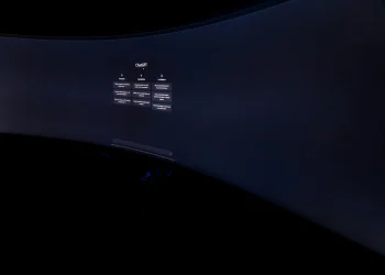 Curved monitor screen showing ChatGPT interface in low-light, focus on technology and AI.