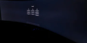 Curved monitor screen showing ChatGPT interface in low-light, focus on technology and AI.