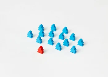 A collection of blue meeple figures with a standout red one on a white background.
