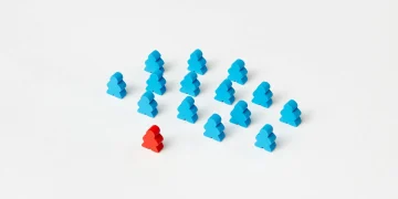 A collection of blue meeple figures with a standout red one on a white background.